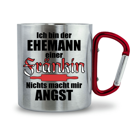 Zeigt eine Edelstahltasse mit Krabinergriff und lustigem Spruch für Ehemänner